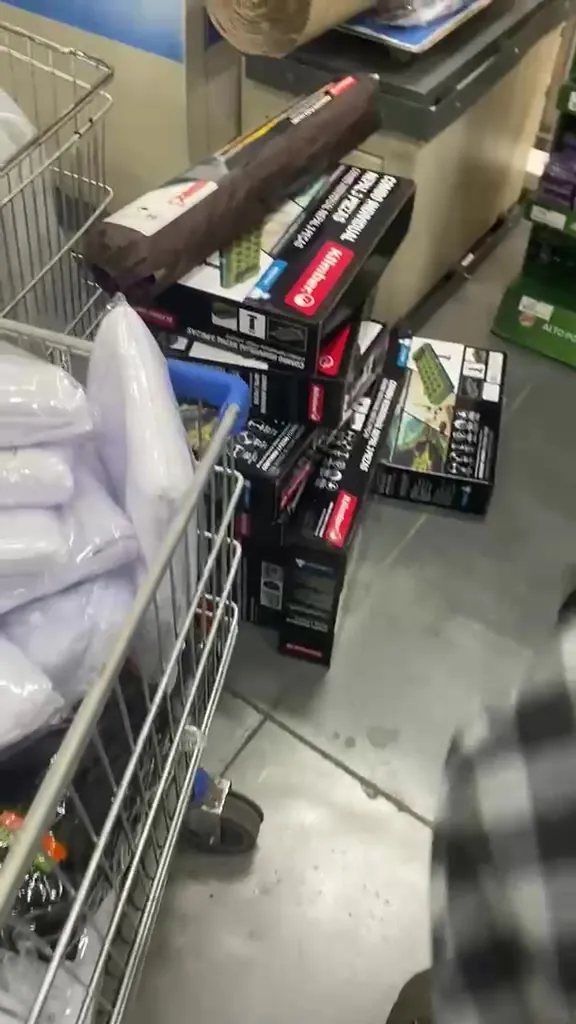 Un carrito de almacén cargado con cajas de colchones inflables y toldillos empacados.