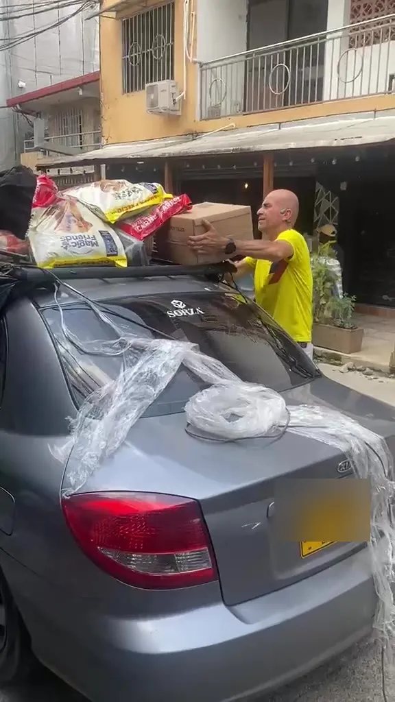 Un carro con bultos de mercado amarrados al techo y cubiertos con plástico, siendo cargado en una calle de Quibdó.