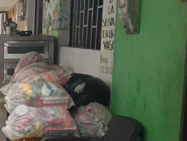 Bolsas de mercado apiladas en el piso junto a una pared, antes de repartirlas.