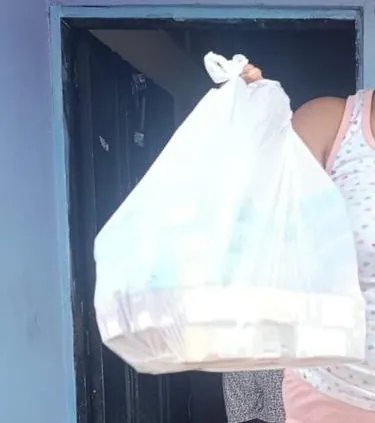 Una bolsa de mercado sostenida en alto en el marco de la puerta de una casa.