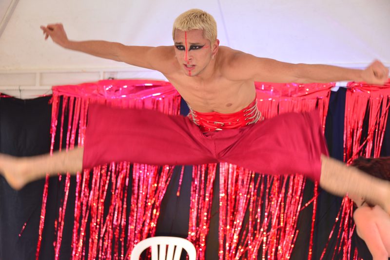 Una persona vestida de rojo extiende los brazos sobre un escenario.
