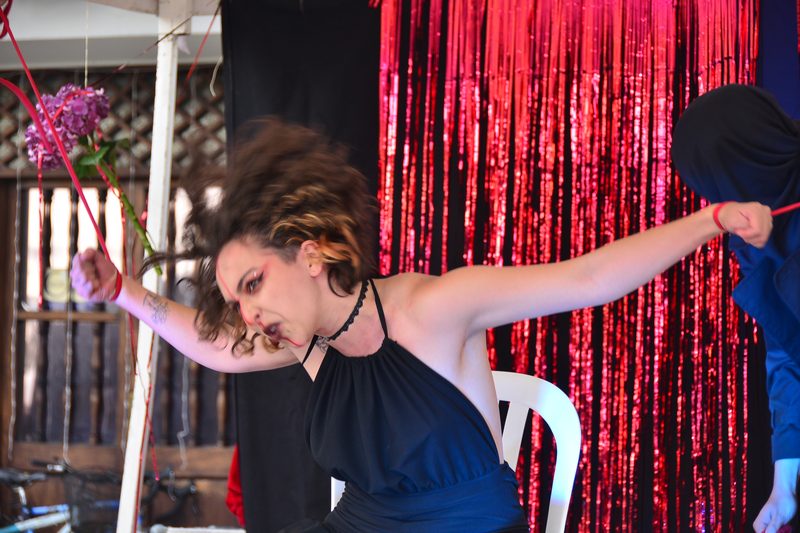 Una artista con vestido oscuro extiende los brazos sobre el escenario.