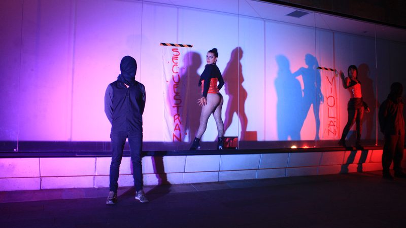 Artistas y sombras aparecen sobre un escenario con luces de colores.