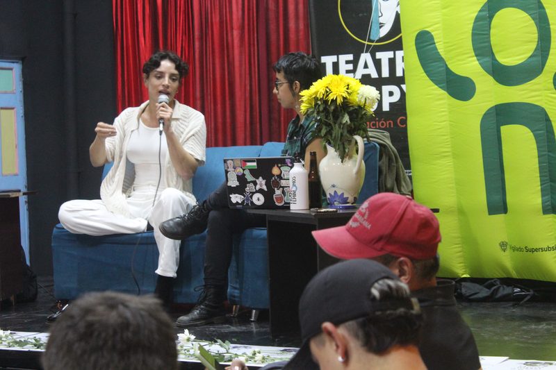 Una persona habla con micrófono durante una conversación ante público.