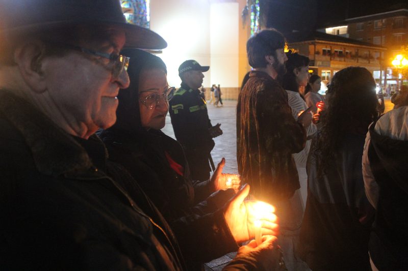 Una persona adulta sostiene una vela encendida entre otras personas.