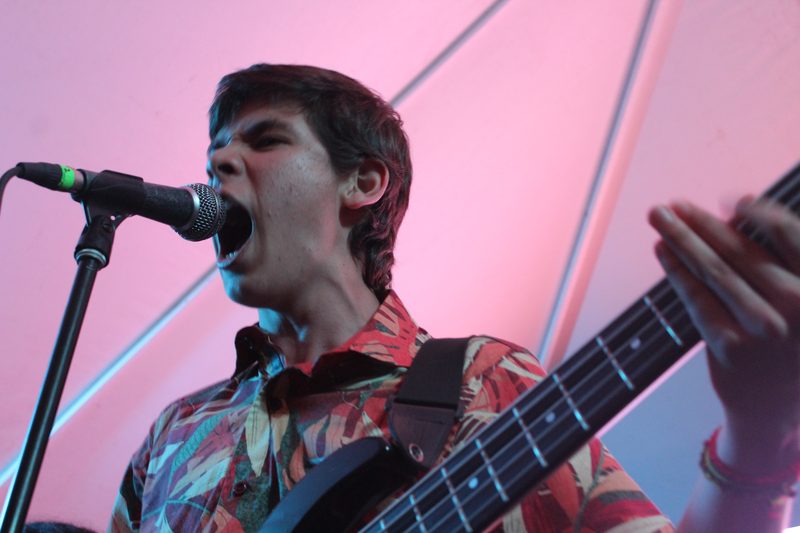 Una persona canta y toca un instrumento frente a un micrófono.