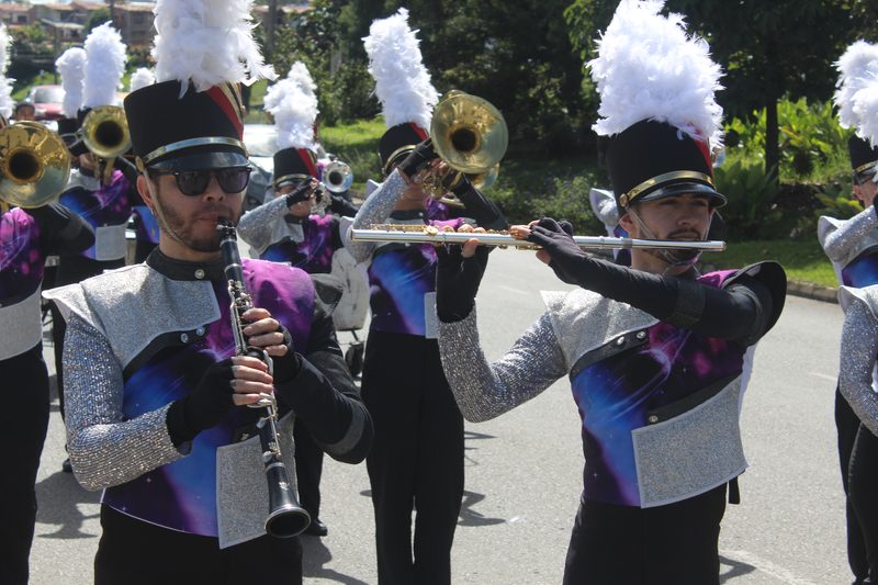 Integrantes de una banda tocan instrumentos de viento en una calle.